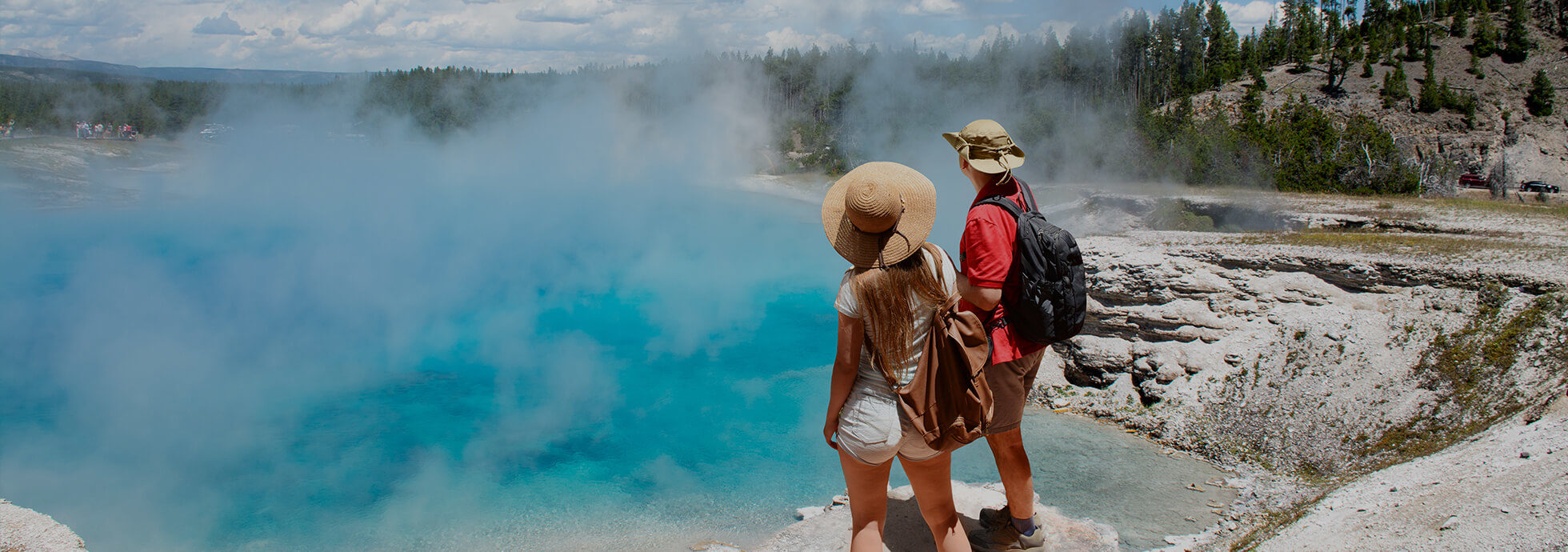 A couple standing over steaming Yellowstone hot springs